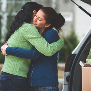Mother hugging daughter while dropping her off at college