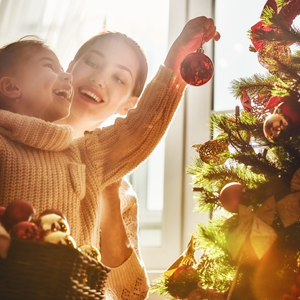 Mother and daughter hanging ornaments on a Christmas tree