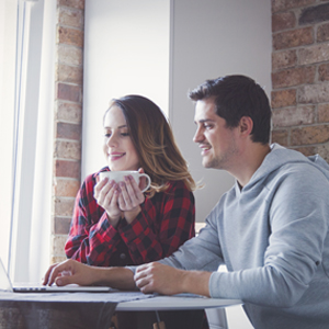 Young couple creating budget on laptop computer